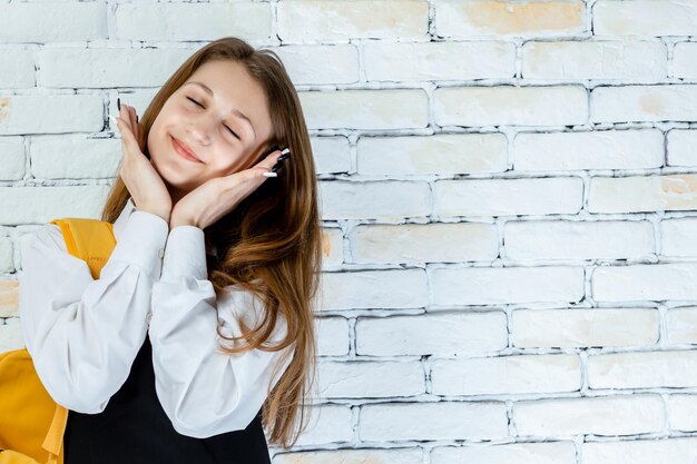 Portret van een schattige studente houdt haar handen voor haar gezicht en voelt zich gelukkig Foto van hoge kwaliteit