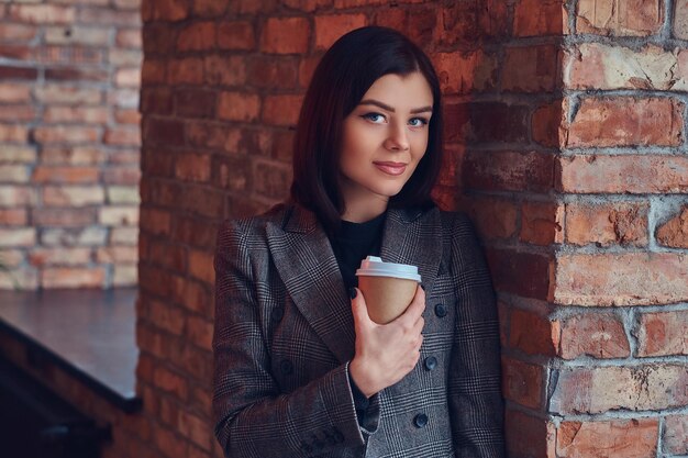 Portret van een schoonheidszakenvrouw houdt een kopje koffie in de ochtend vast