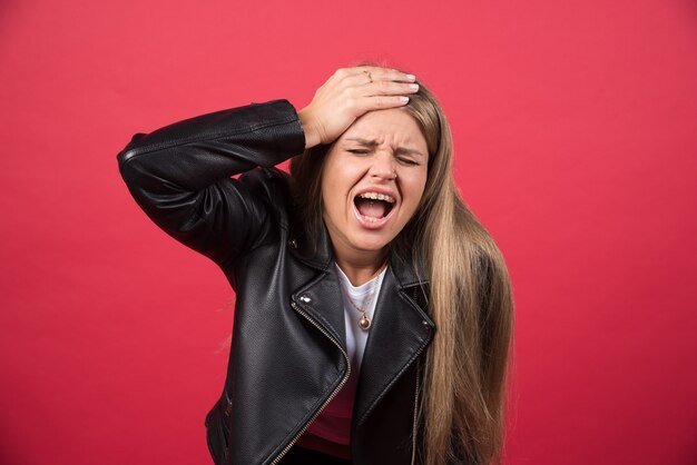 Portret van een schreeuwende dame met gesloten ogen die haar hoofd aanraakt