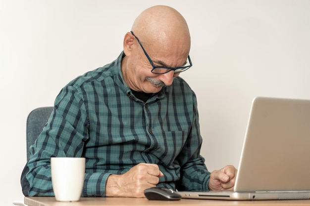 Portret van een senior man die thuis op een laptop werkt
