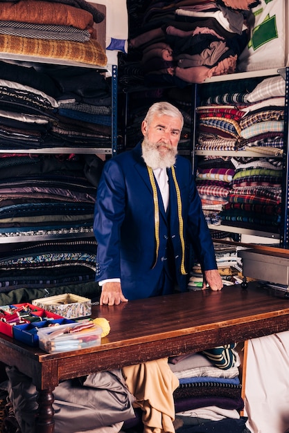 Portret van een senior mannelijke modeontwerper in zijn kledingwinkel