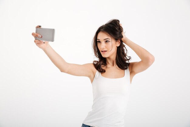 Portret van een sensuele vrouw gekleed in tanktop die een selfie neemt