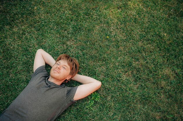 Portret van een serene volwassen man die op het gras ligt