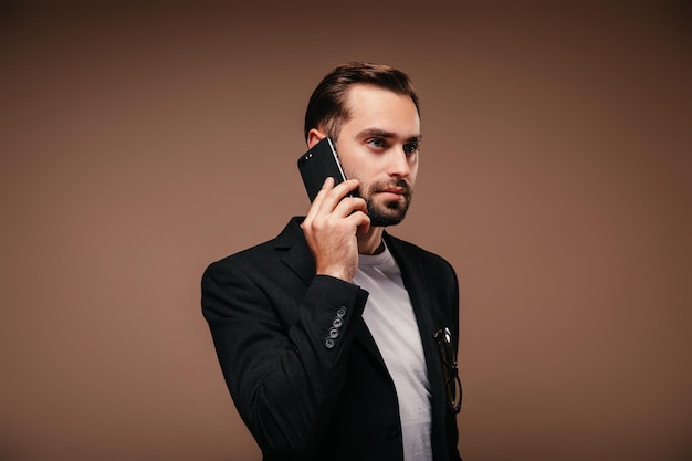 Portret van een serieuze man in een zwart pak die aan de telefoon praat