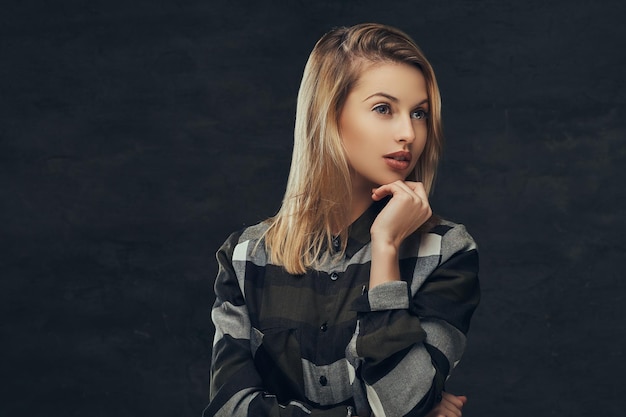 Portret van een sexy blond meisje in een fleece shirt, poseren in een studio. Geïsoleerd op een donkere achtergrond.