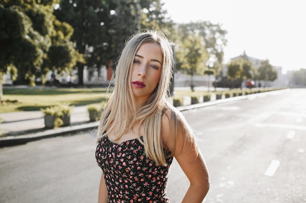 Portret van een sexy blonde jonge vrouw met dagelijkse make-up staat in het midden van de weg