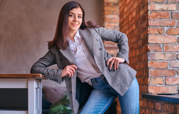 Portret van een sexy brunette leunend op een tafel in een kamer met lo