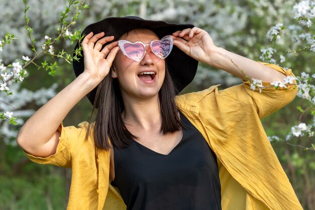 Portret van een stijlvol meisje tussen bloeiende bomen in het bos.