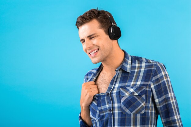 Portret van een stijlvolle, aantrekkelijke, knappe jongeman die naar muziek luistert op een draadloze koptelefoon met een leuke moderne stijl, een gelukkige emotionele stemming