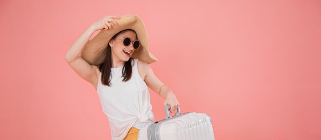 Portret van een stijlvolle jonge vrouw in een hoed met een koffer