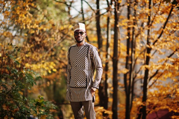 Portret van een stijlvolle zwarte Afro-Amerikaanse man met hoed en zonnebril tegen een zonnige herfstachtergrond