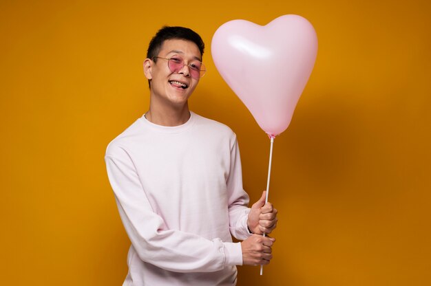 Portret van een tiener die een hartvormige ballon vasthoudt en zijn tong uitsteekt