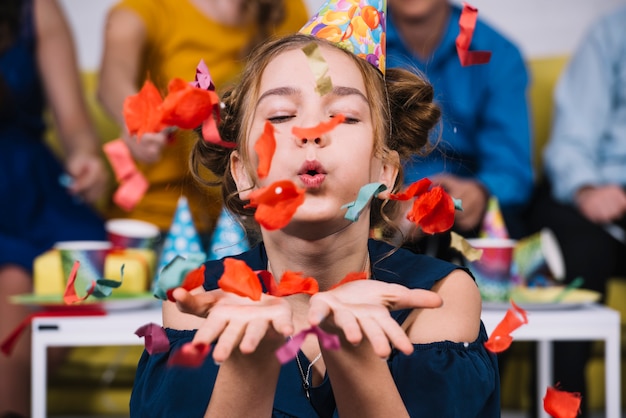 Portret van een tiener meisje waait confetti op haar verjaardag