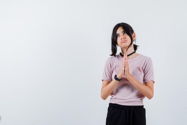 Portret van een tienermeisje dat een gebedsgebaar vasthoudt in een paars t-shirt met een zwarte ketting en er hopeloos uitziet Gratis Foto