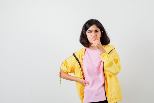 Portret van een tienermeisje dat wegwijst in t-shirt, jas en boos vooraanzicht kijkt