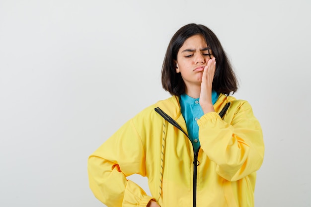 Gratis foto portret van een tienermeisje met vreselijke kiespijn in een gele jas en neergeslagen vooraanzicht