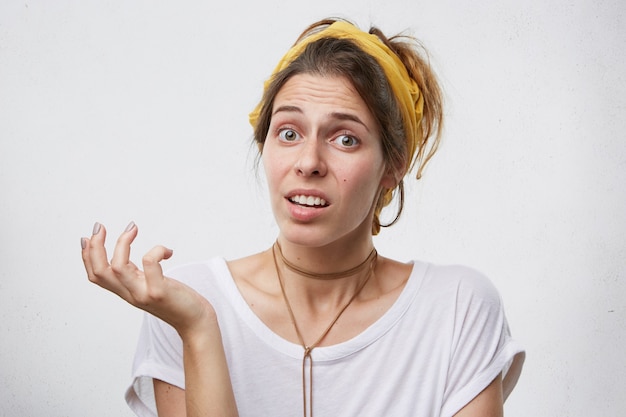 Portret van een twijfelachtige vrouw die met verbazing naar de camera kijkt