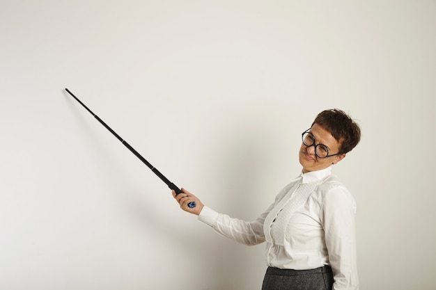 Portret van een vermoeide en weerzinwekkende vrouwelijke leraar met zwarte aanwijzer en conservatieve kleding die een les een leeg whiteboard onderwijst