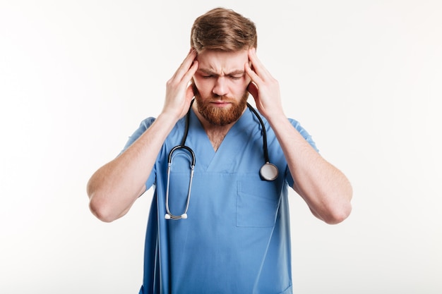 Portret van een vermoeide mannelijke dokter die aan een hoofdpijn lijdt