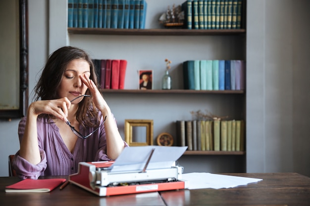 Portret van een vermoeide vrouw journalist zitten aan de tafel