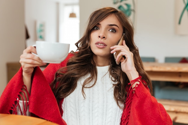 Portret van een verraste vrouw die op mobiele telefoon spreekt