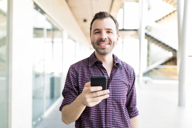 Portret van een volwassen man die op mobiele telefoon chat met een vriend in het winkelcentrum