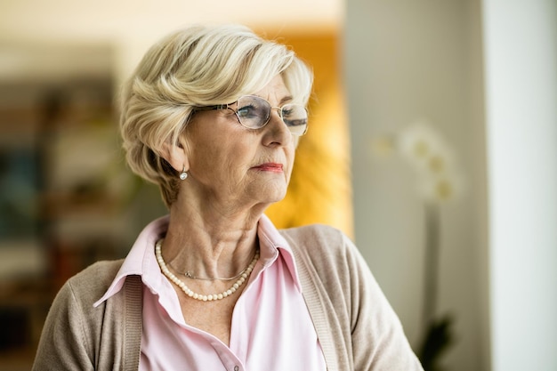 Portret van een volwassen vrouw die dag droomt terwijl ze thuis ontspant