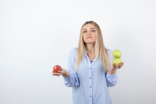 Portret van een vrij aantrekkelijk vrouwenmodel dat staat en verse appels vasthoudt.