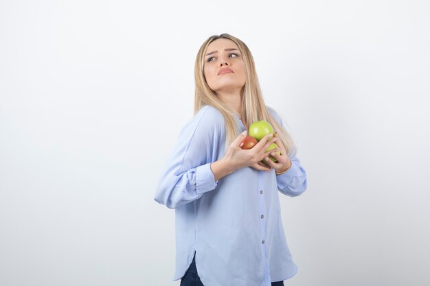 Portret van een vrij aantrekkelijk vrouwenmodel dat staat en verse appels vasthoudt.