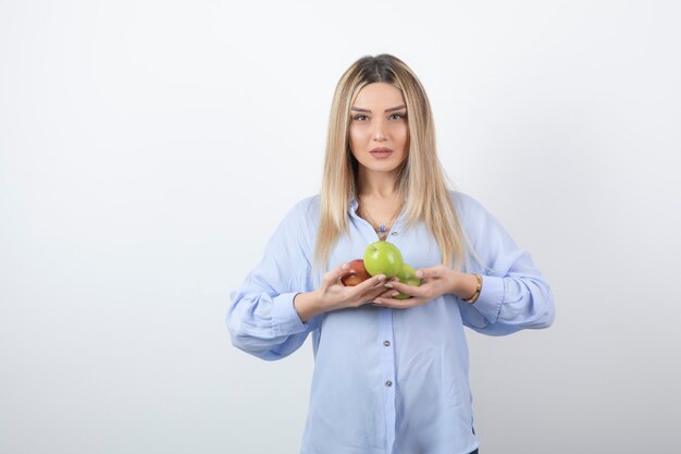 Portret van een vrij aantrekkelijk vrouwenmodel dat staat en verse appels vasthoudt.