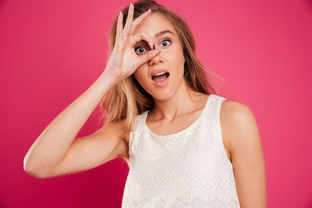 Portret van een vrolijk mooi meisje dat in kleding door vingers kijkt