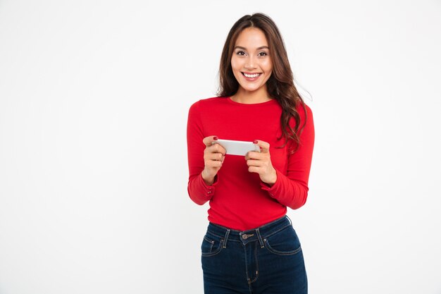Portret van een vrolijke jonge Aziatische vrouw die apps speelt