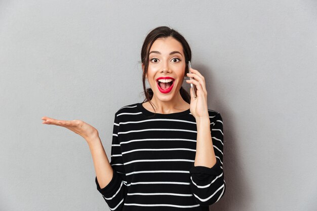 Portret van een vrolijke vrouw die op mobiele telefoon spreekt