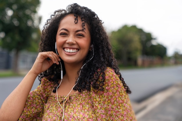 Gratis foto portret van een vrouw die buiten naar muziek luistert op een koptelefoon