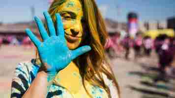 Gratis foto portret van een vrouw die camera bekijkt die geschilderde blauwe hand toont