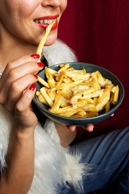 Portret van een vrouw die een schotel poutine eet