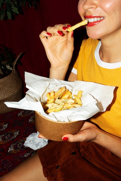 Gratis foto portret van een vrouw die een schotel poutine eet