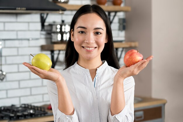 Portret van een vrouw die gezonde groene en rode appel in keuken toont