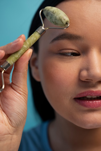 Gratis foto portret van een vrouw die jade roller op haar gezicht gebruikt