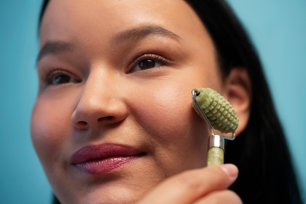 Gratis foto portret van een vrouw die jade roller op haar gezicht gebruikt