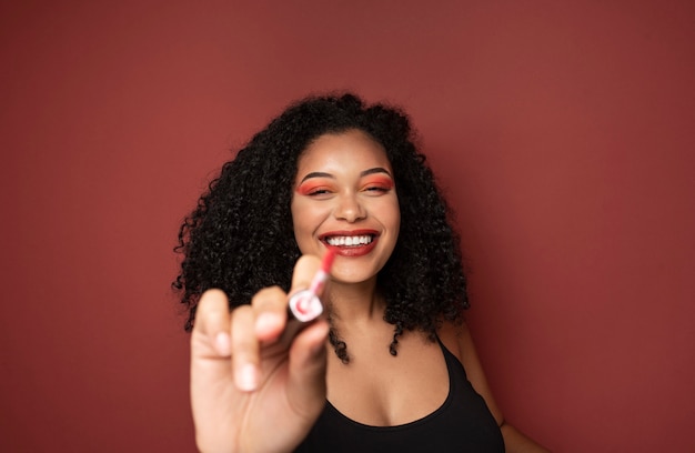 Portret van een vrouw die lacht en wijst met een lippenstiftapplier