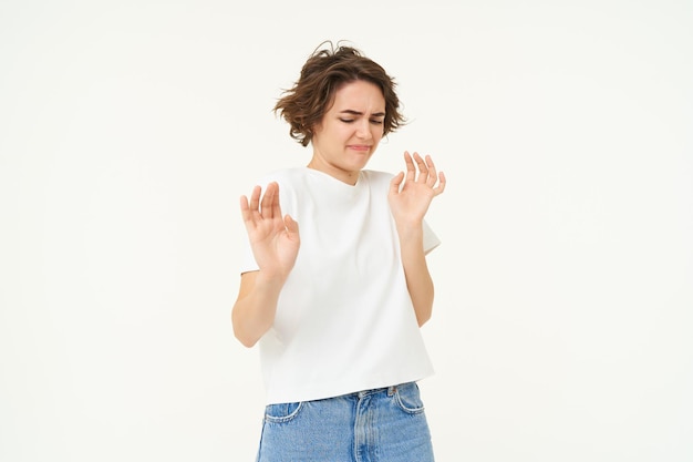 Gratis foto portret van een vrouw die met afkeer kijkt en iets afwijst en de handen omhoog steekt in een defensief gebaar