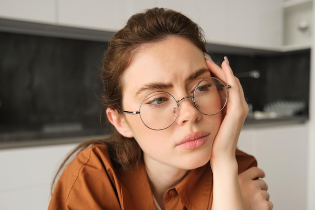 Gratis foto portret van een vrouw die nadenkt over iets met betrekking tot het dragen van een bril, het aanraken van het hoofd, bezorgd zitten