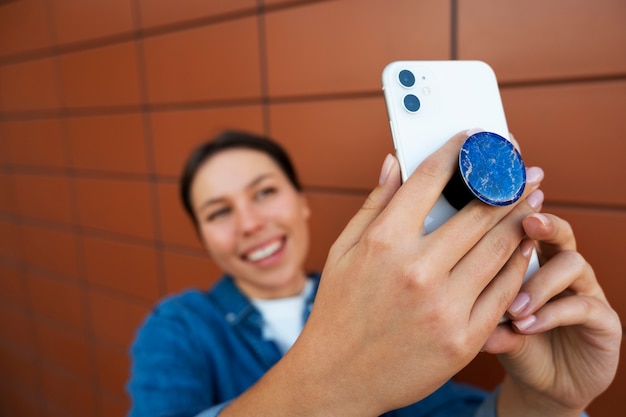 Portret van een vrouw die smartphone met pop-socket buitenshuis gebruikt