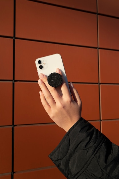 Gratis foto portret van een vrouw die smartphone met pop-socket buitenshuis gebruikt