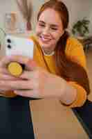 Gratis foto portret van een vrouw die thuis een smartphone gebruikt met een pop-socket