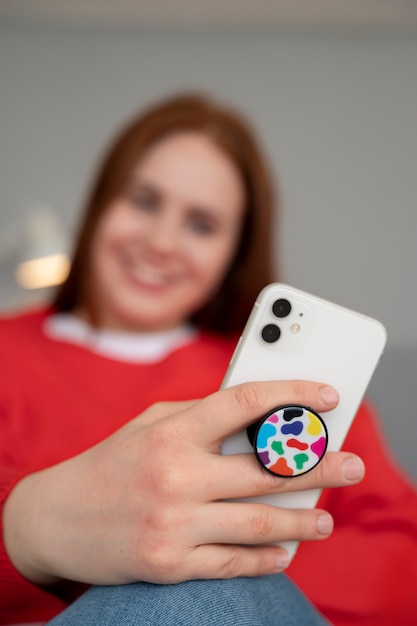 Portret van een vrouw die thuis een smartphone gebruikt met een pop-socket