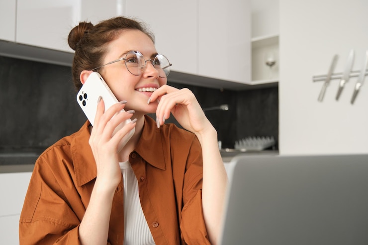 Gratis Foto portret van een vrouw die thuis werkt met een laptop en een telefoontje maakt met een smartphone