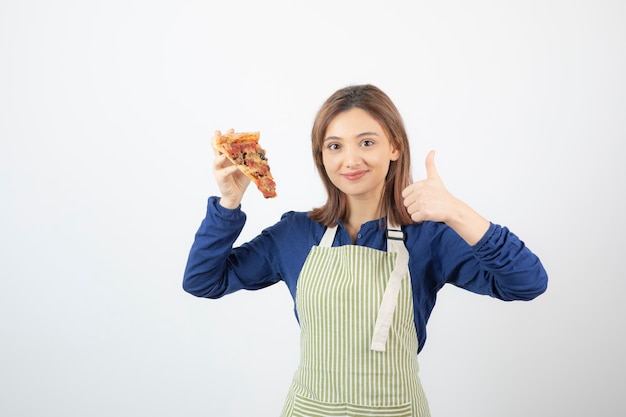 Portret van een vrouw in een schort die een stuk pizza op wit toont