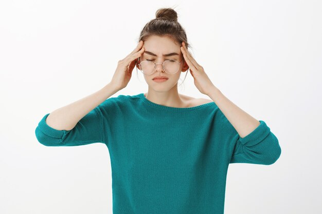 Portret van een vrouw met een bril met hoofdpijn, duizeligheid of koorts, migraine
